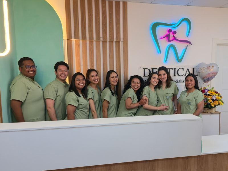 The Dentical team at the clinic’s front desk, under the neon logo.